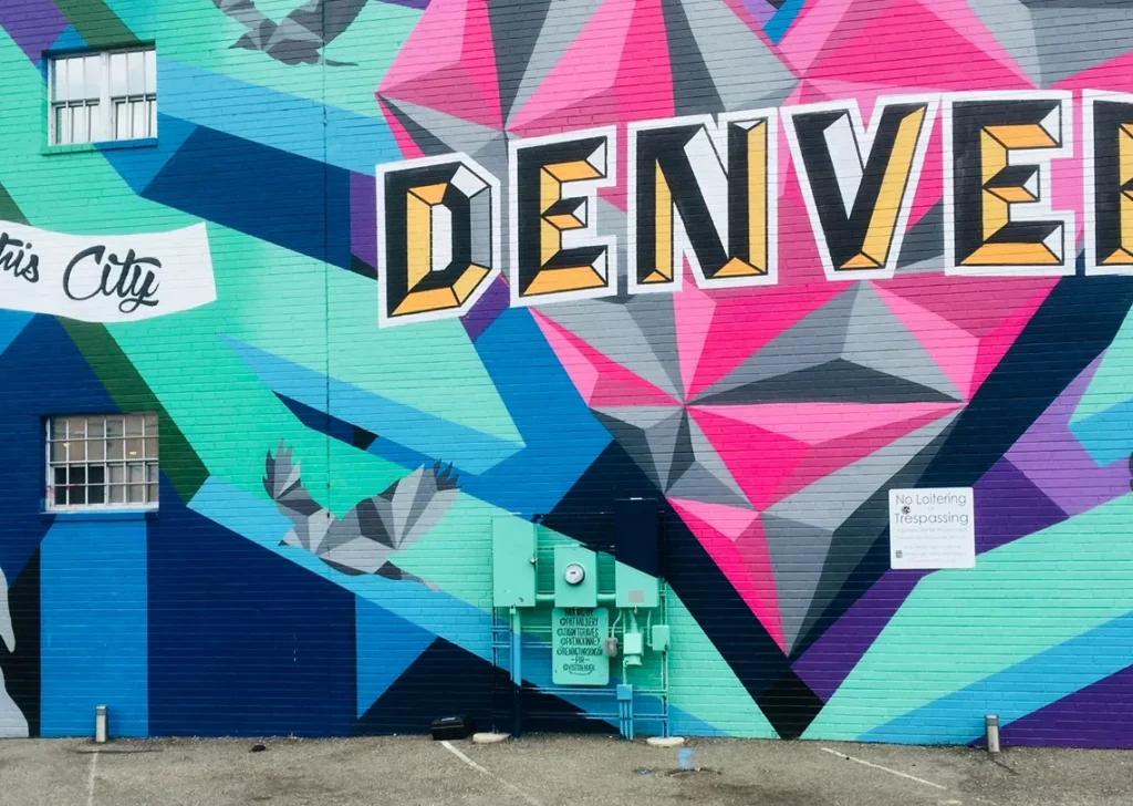 Colorful geometric mural featuring the word Denver on a brick building wall