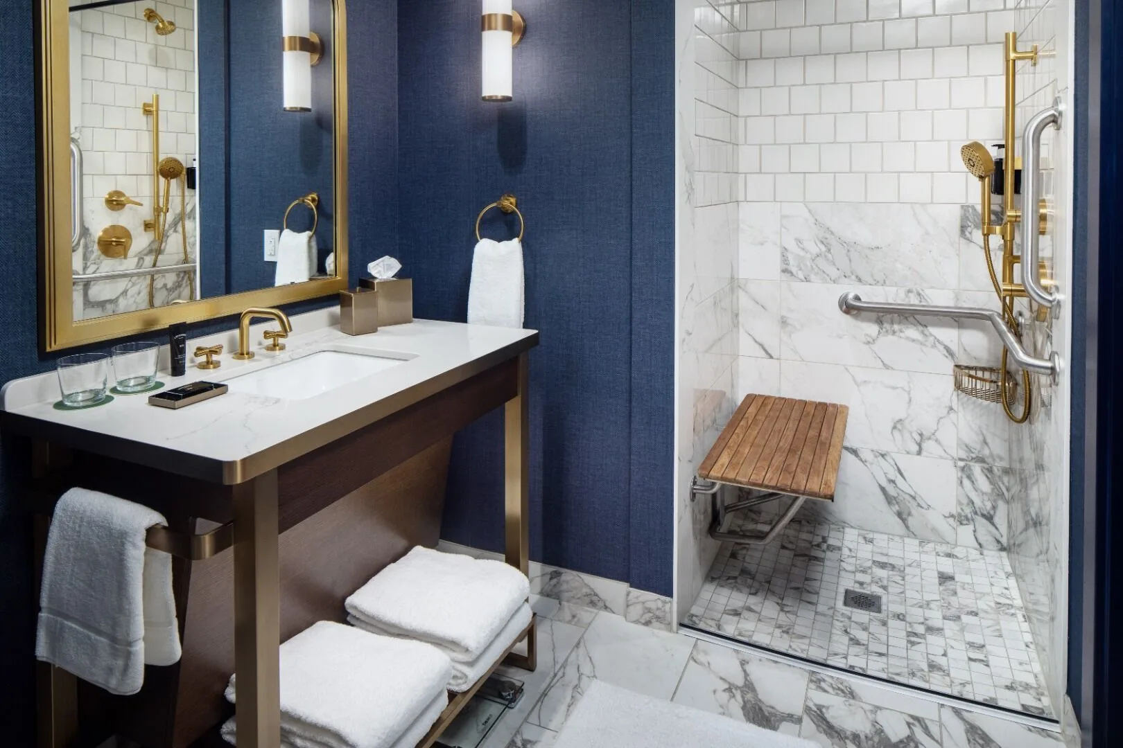 Luxury hotel bathroom with blue walls, marble shower, and gold fixtures