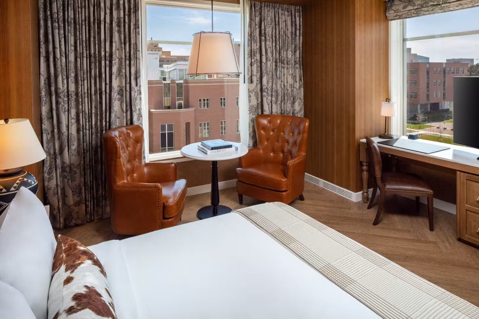 Hotel room interior with leather armchairs, desk, and city view