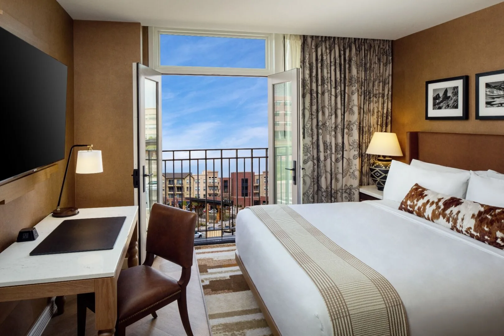 Hotel room with king bed, balcony access, and city view