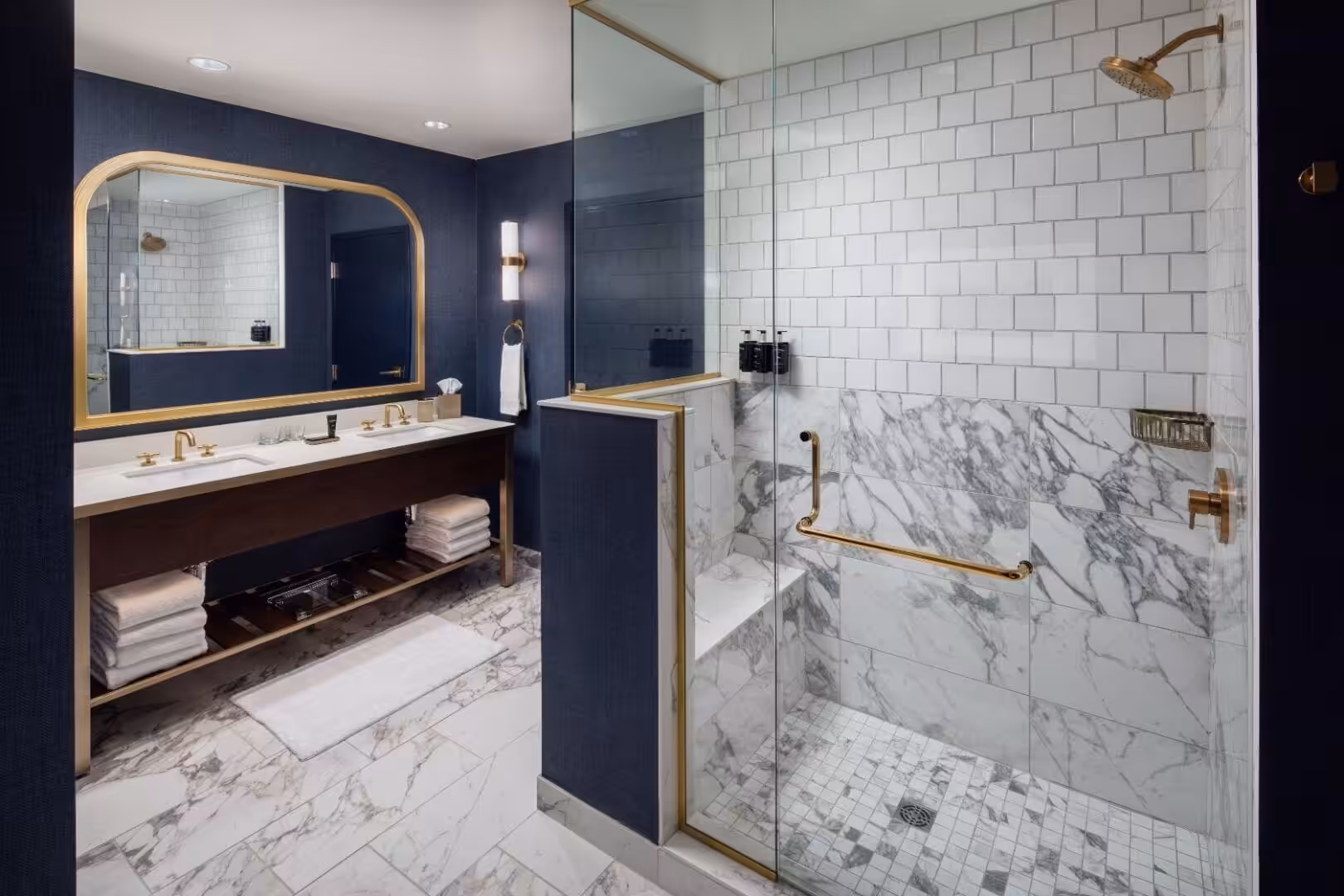 Modern bathroom featuring marble floors, glass shower, and gold fixtures at The Benson Hotel.