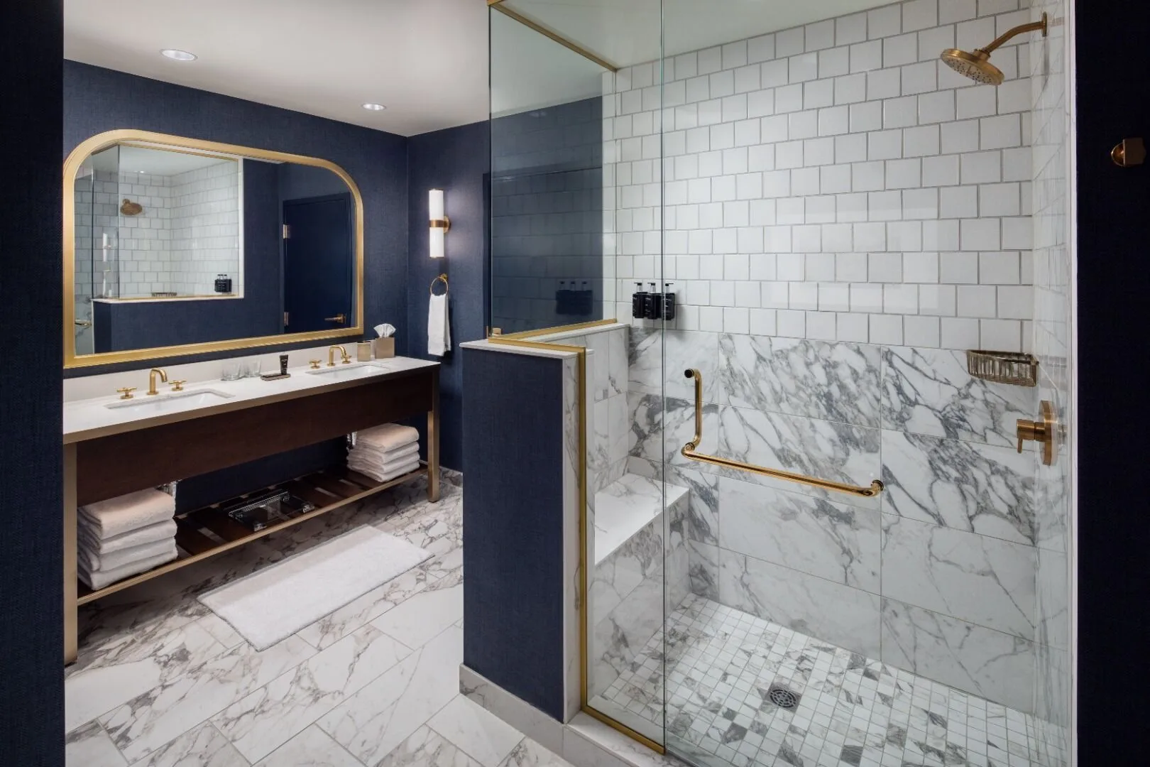 Modern bathroom featuring marble floors, glass shower, and gold fixtures at The Benson Hotel.