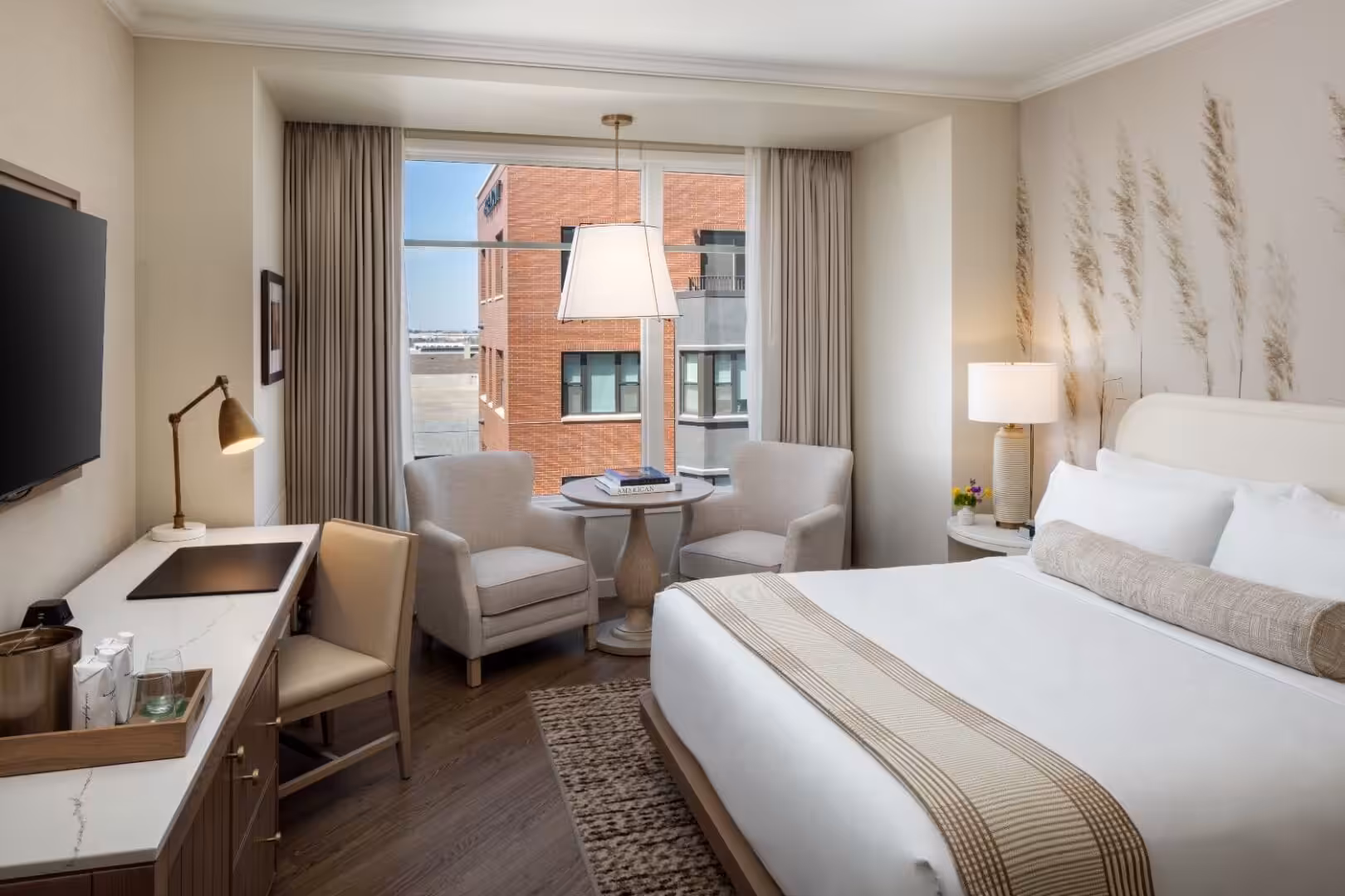 Modern hotel room with king bed, seating area, and city view at The Benson Hotel.